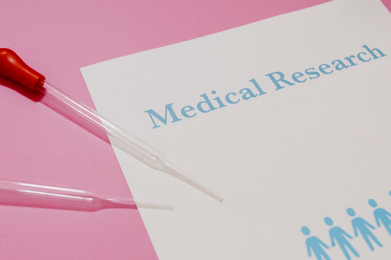 services-04 Close-up of a medical research document and pipette on a pink surface, highlighting scientific research and healthcare.
